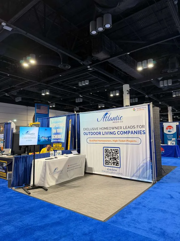 The Atlantic Media Company booth with a branded table and pull-up banners beside an American flag at a national pool and spa show