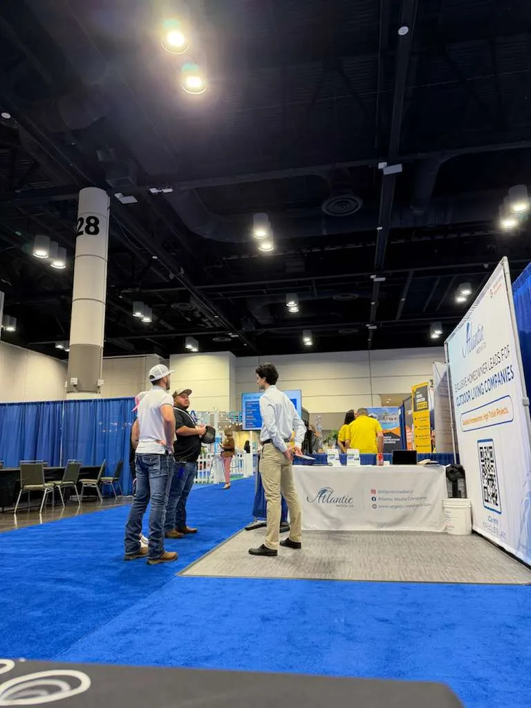 Two contractors talking with an Atlantic Media Company team member in front of the booth banner