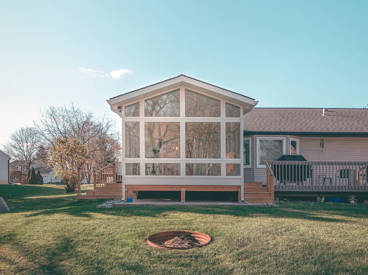 A clean, high-end four-season sunroom addition on a well-kept home in bright natural daylight